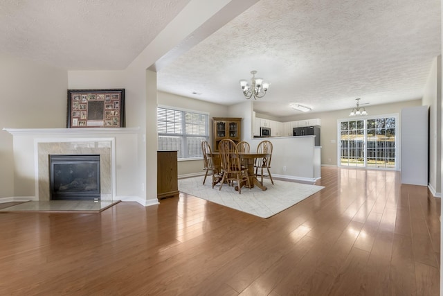 unfurnished dining area with a high end fireplace, an inviting chandelier, light wood-type flooring, and a wealth of natural light