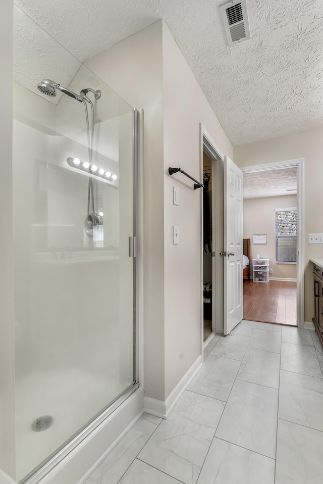 bathroom featuring visible vents, a textured ceiling, marble finish floor, and a shower stall