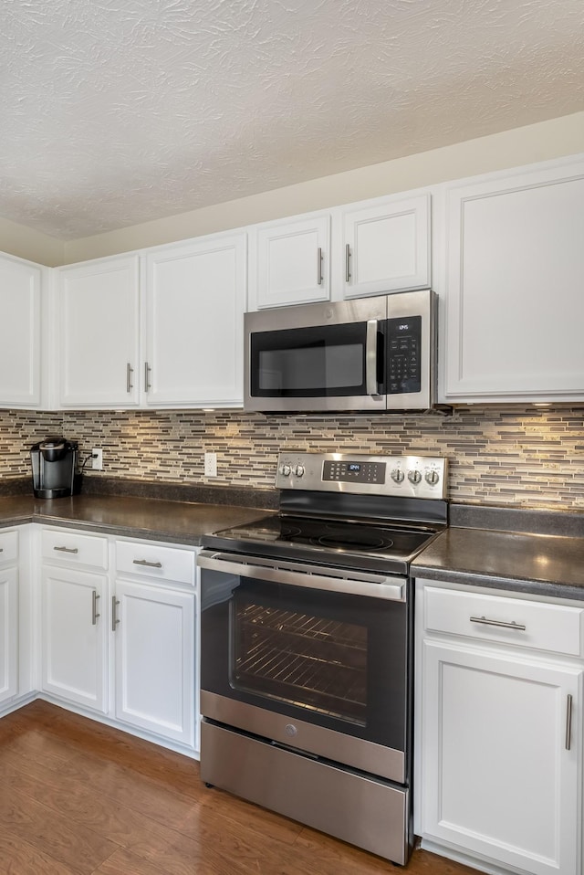 kitchen with stainless steel appliances, dark countertops, and white cabinetry