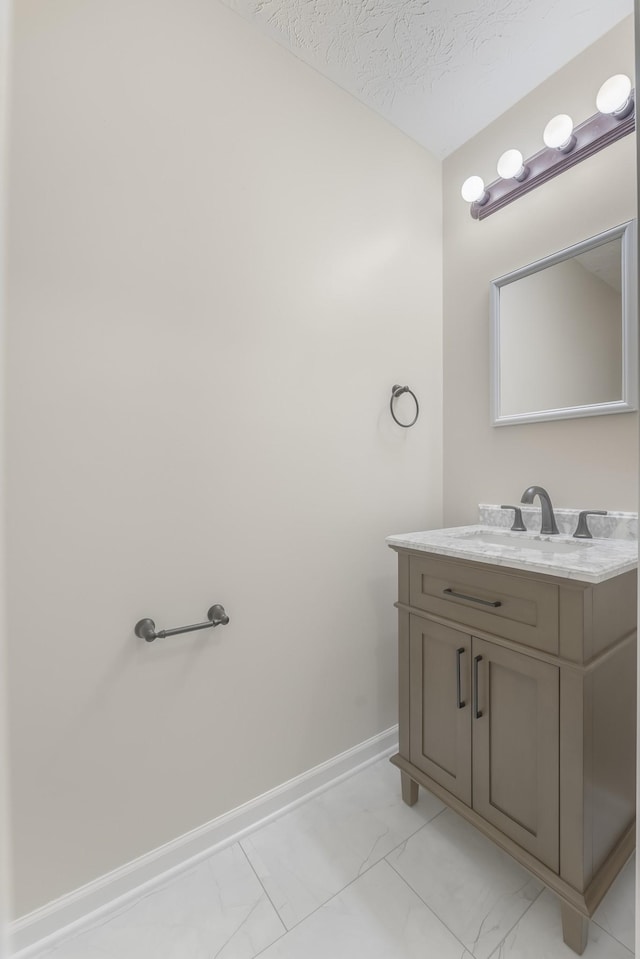 bathroom featuring vanity, baseboards, marble finish floor, and a textured ceiling