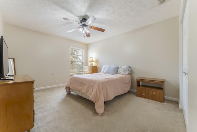 bedroom with visible vents, a ceiling fan, a textured ceiling, baseboards, and light colored carpet