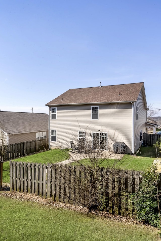 back of house with a fenced backyard and a yard