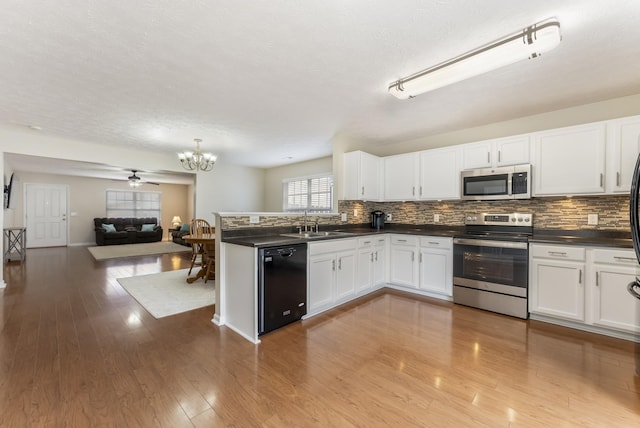 kitchen featuring dark countertops, open floor plan, decorative backsplash, white cabinets, and stainless steel appliances