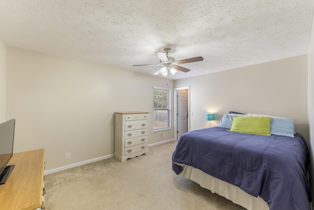 bedroom featuring baseboards, light colored carpet, a ceiling fan, and a textured ceiling