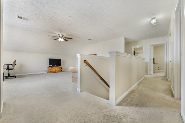 corridor featuring visible vents, carpet, lofted ceiling, an upstairs landing, and a textured ceiling