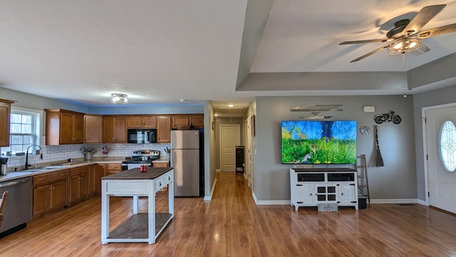 kitchen featuring a sink, backsplash, appliances with stainless steel finishes, and wood finished floors