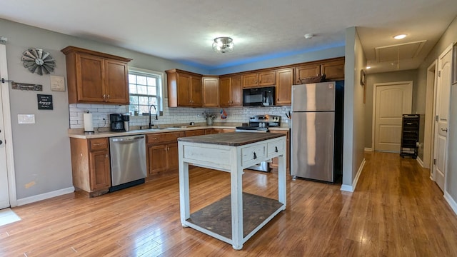 kitchen featuring brown cabinetry, decorative backsplash, light wood-style flooring, and stainless steel appliances