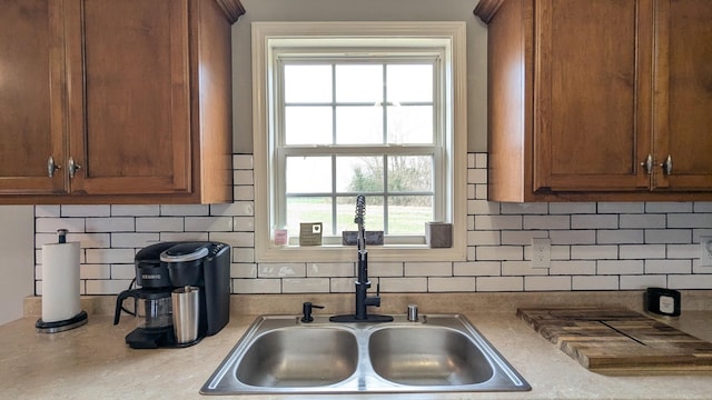 kitchen with light countertops, brown cabinets, backsplash, and a sink