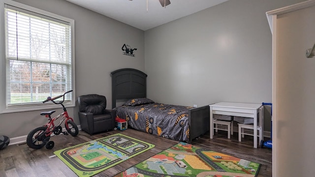 bedroom featuring baseboards, wood finished floors, and a ceiling fan