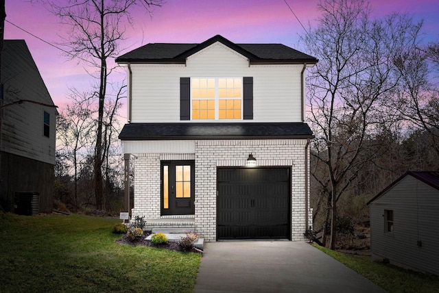 traditional-style home featuring driveway, a yard, roof with shingles, a garage, and brick siding