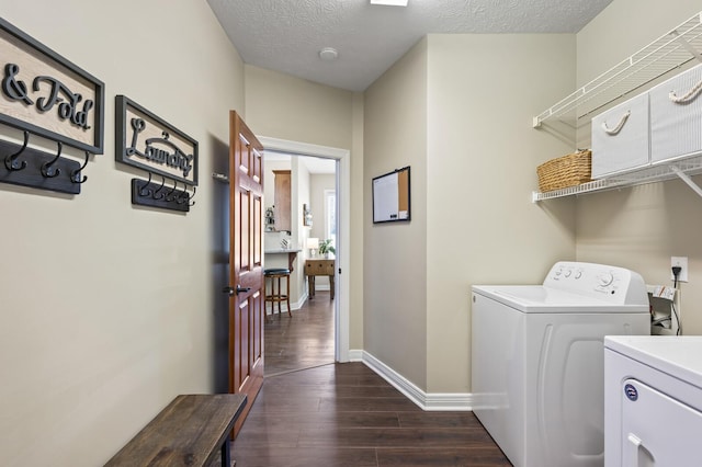 laundry room featuring a textured ceiling, baseboards, laundry area, dark wood finished floors, and washing machine and dryer