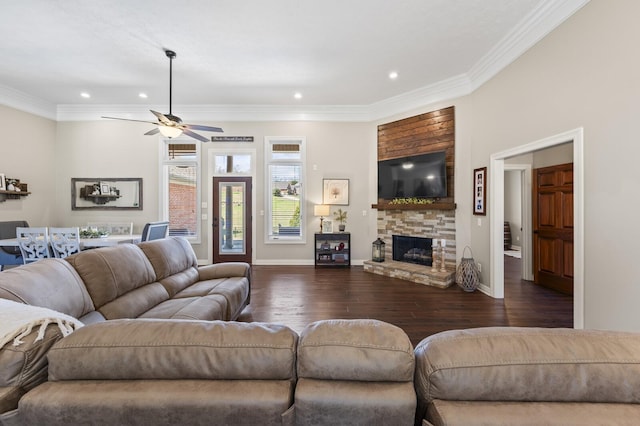 living room with dark wood-style flooring, baseboards, a fireplace, ornamental molding, and ceiling fan
