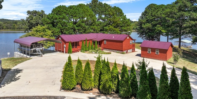 view of front of house featuring a carport, a water view, driveway, and metal roof