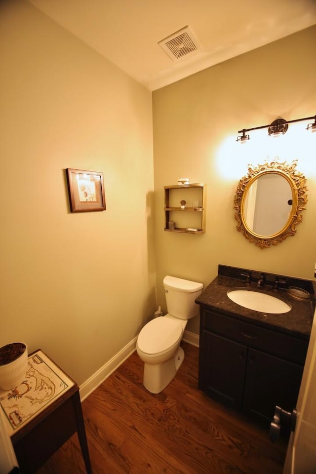 bathroom with visible vents, toilet, wood finished floors, baseboards, and vanity