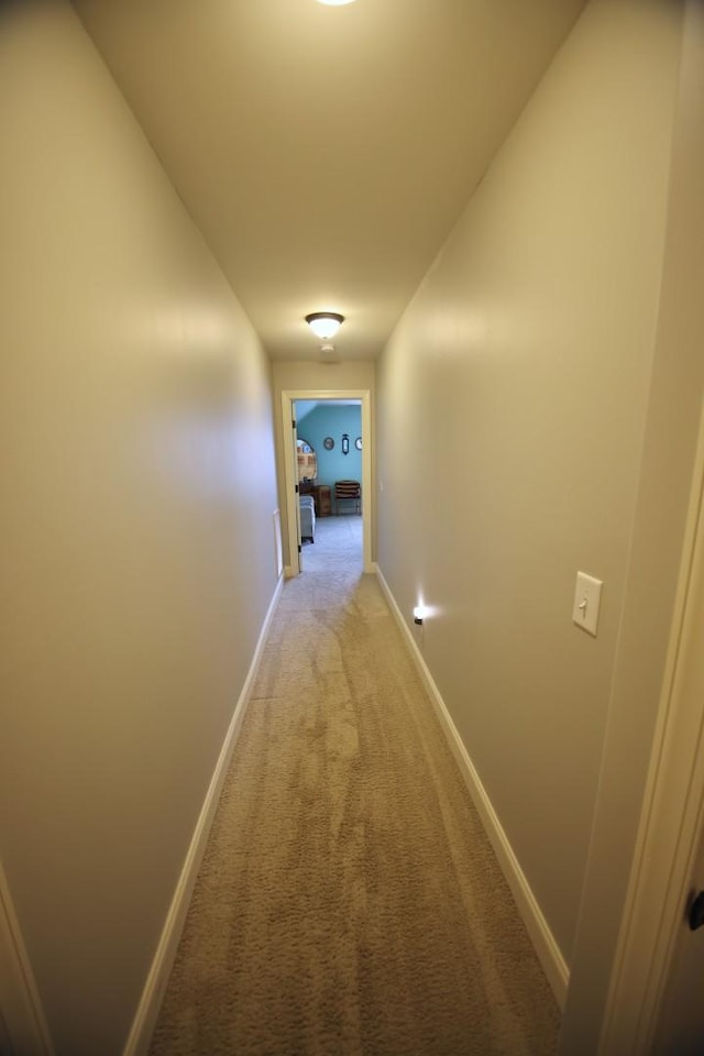 hall with baseboards and light carpet