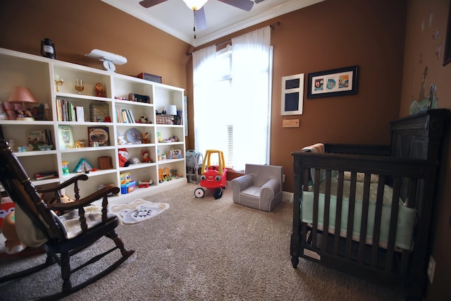 carpeted bedroom with a crib, ceiling fan, and ornamental molding