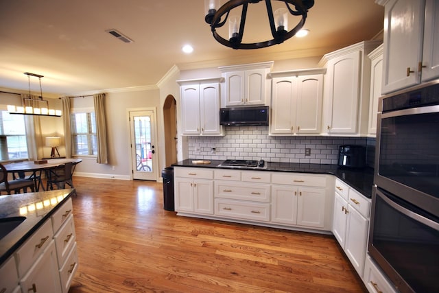 kitchen with visible vents, ornamental molding, stainless steel appliances, white cabinetry, and a notable chandelier