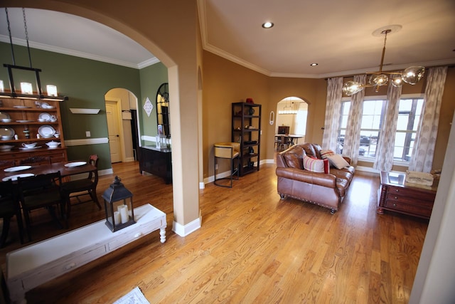 living area featuring arched walkways, crown molding, baseboards, and wood finished floors