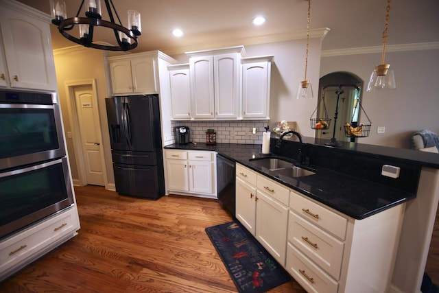 kitchen with a notable chandelier, black appliances, a sink, white cabinetry, and a peninsula