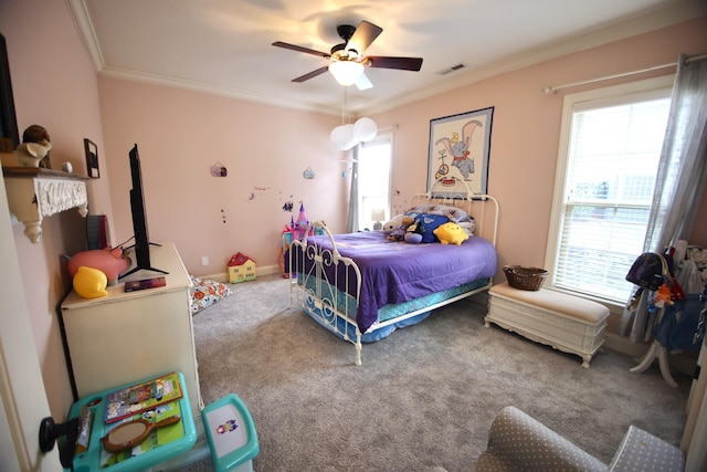 carpeted bedroom with visible vents, baseboards, ornamental molding, and a ceiling fan
