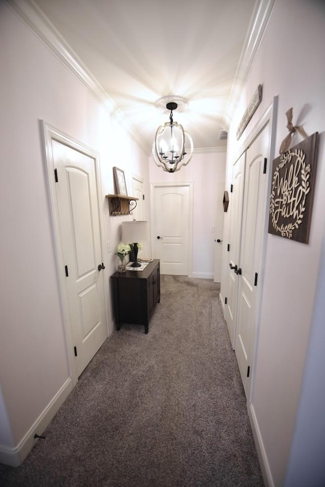 hall with baseboards, carpet floors, a notable chandelier, and ornamental molding