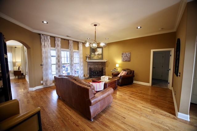living room with crown molding, light wood-style flooring, and arched walkways