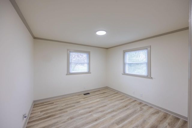 unfurnished room with visible vents, baseboards, crown molding, and light wood-style floors