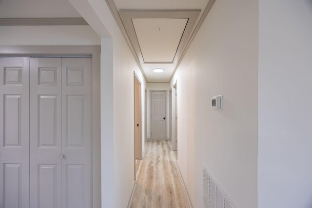 hall featuring attic access, baseboards, visible vents, and light wood-type flooring