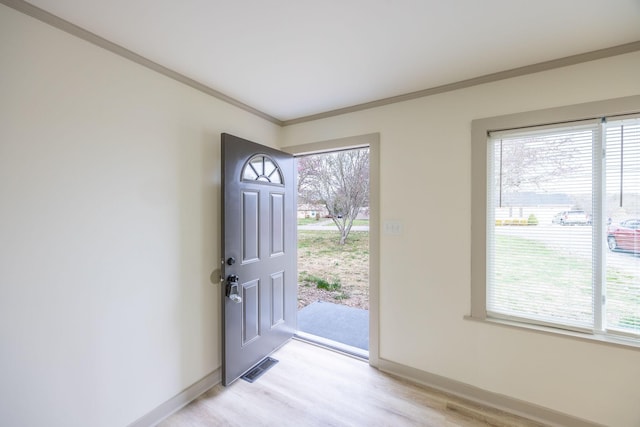 entrance foyer with visible vents, baseboards, light wood-style floors, and ornamental molding