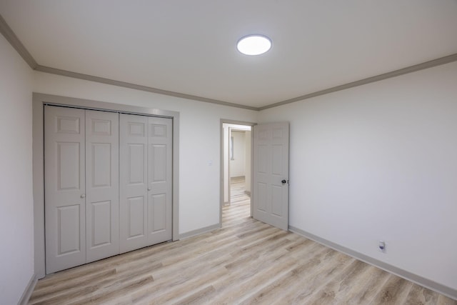 unfurnished bedroom with baseboards, light wood-type flooring, a closet, and ornamental molding