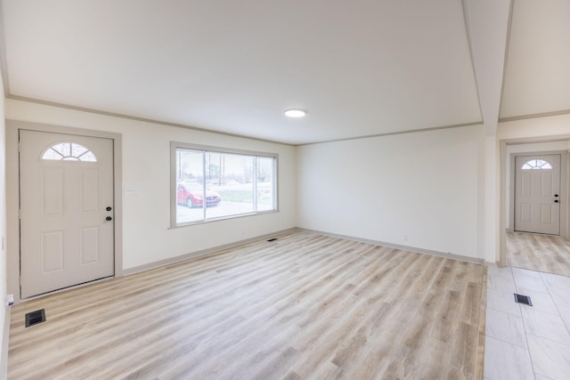 entrance foyer featuring visible vents, baseboards, ornamental molding, and light wood finished floors