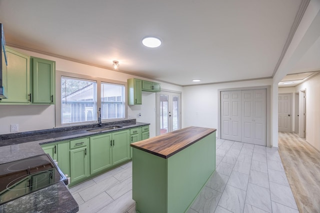 kitchen featuring wood counters, green cabinets, french doors, and a sink