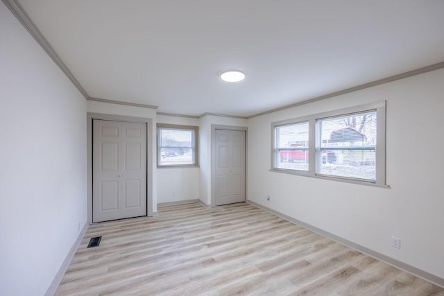unfurnished bedroom featuring light wood-type flooring, multiple windows, baseboards, and crown molding