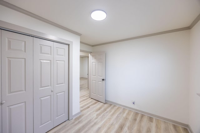 unfurnished bedroom with crown molding, a closet, and light wood finished floors