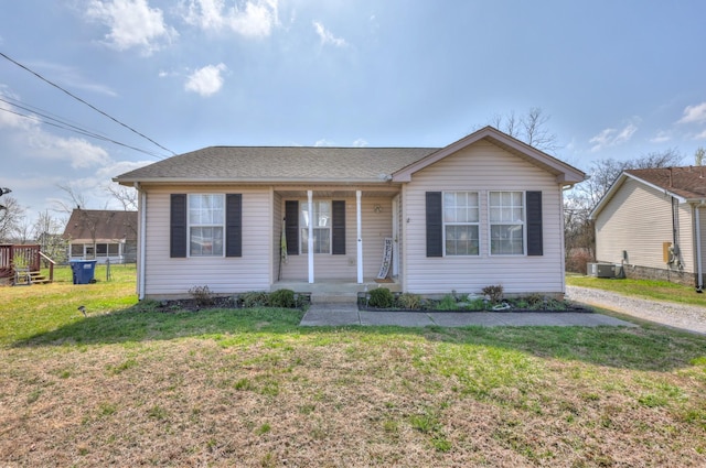 view of front of home featuring central AC unit, roof with shingles, covered porch, and a front yard