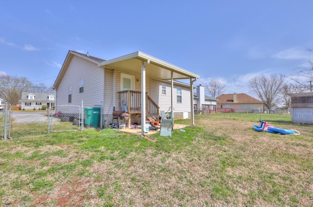 back of house featuring fence, a yard, and a gate