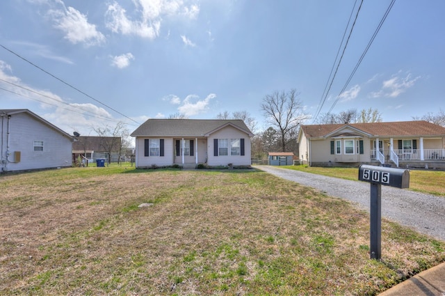 bungalow-style home featuring an outbuilding, driveway, and a front lawn