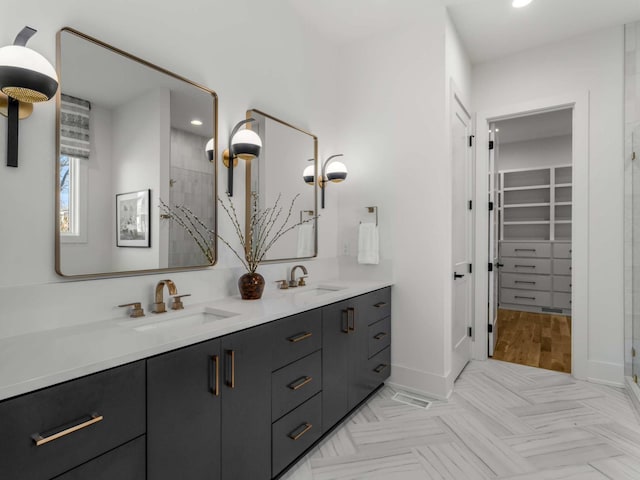 bathroom featuring double vanity, tiled shower, a sink, and a spacious closet
