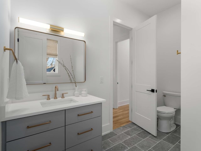 bathroom featuring toilet, baseboards, tile patterned floors, and vanity