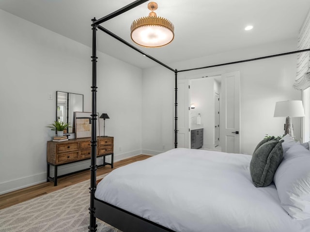 bedroom with baseboards, recessed lighting, ensuite bath, and wood finished floors