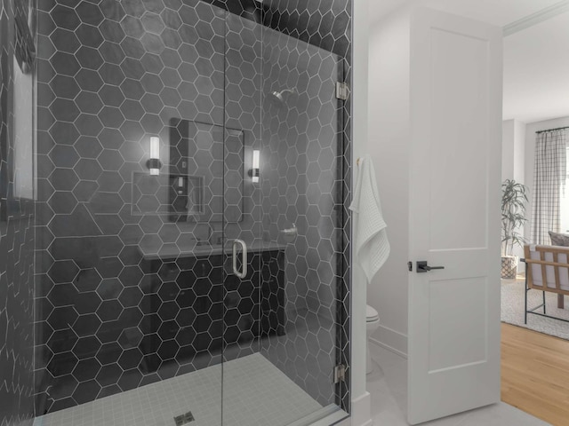 bathroom with toilet, wood finished floors, and a stall shower
