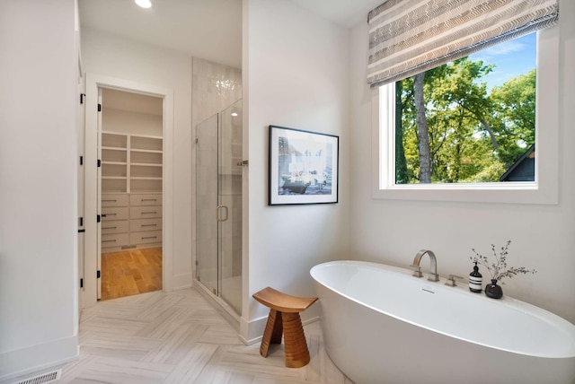 bathroom featuring a freestanding bath, a walk in closet, a shower stall, and visible vents
