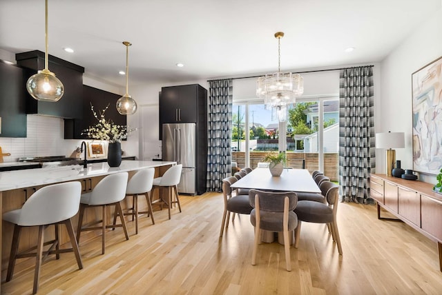 dining space with recessed lighting, light wood-style flooring, and a notable chandelier