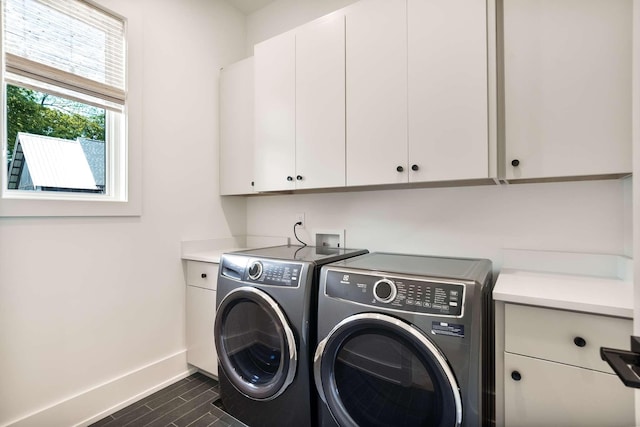 clothes washing area with washer and dryer, baseboards, and cabinet space