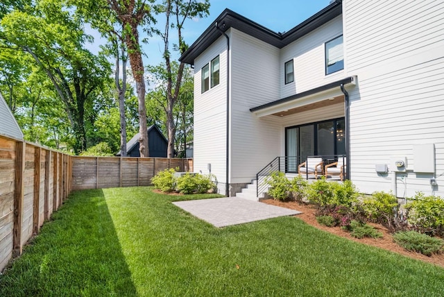 back of property featuring a yard, a fenced backyard, and a patio area