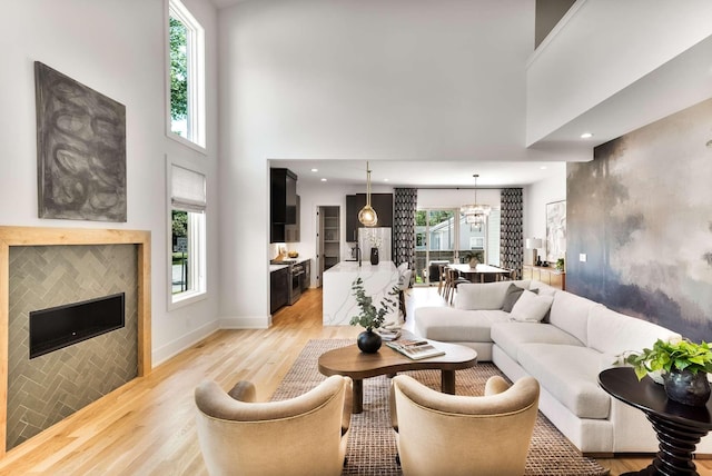 living area with an inviting chandelier, plenty of natural light, and light wood-type flooring