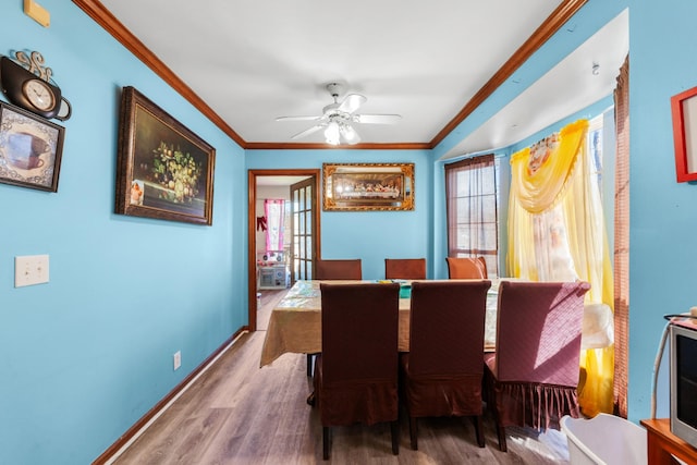 dining room featuring crown molding, wood finished floors, baseboards, and ceiling fan