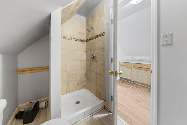 full bath featuring baseboards, wood finished floors, a stall shower, and vaulted ceiling