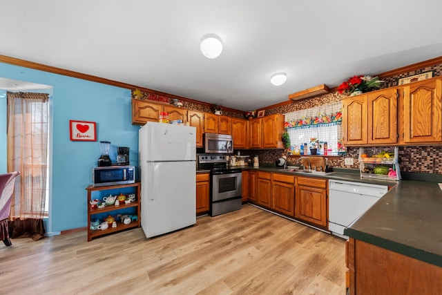 kitchen featuring brown cabinetry, appliances with stainless steel finishes, dark countertops, and a sink