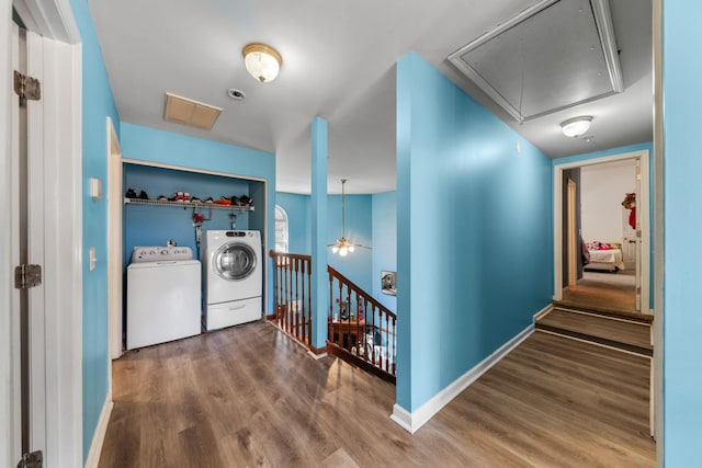 corridor with washing machine and clothes dryer, baseboards, attic access, an upstairs landing, and wood finished floors